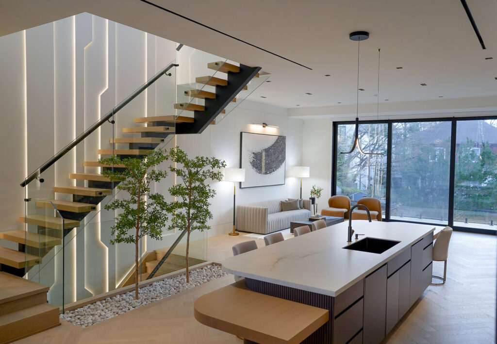 Modern custom home interior Toronto featuring floating wood staircase, glass railing, and open-concept kitchen with large windows