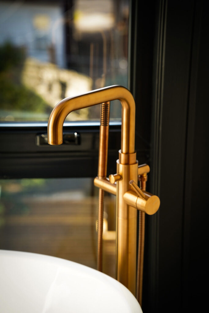 Luxury bathroom fixture Toronto featuring brushed gold freestanding faucet with modern sink and window view