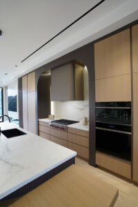 Modern custom kitchen Toronto with built-in cabinetry, stone backsplash, and integrated appliances