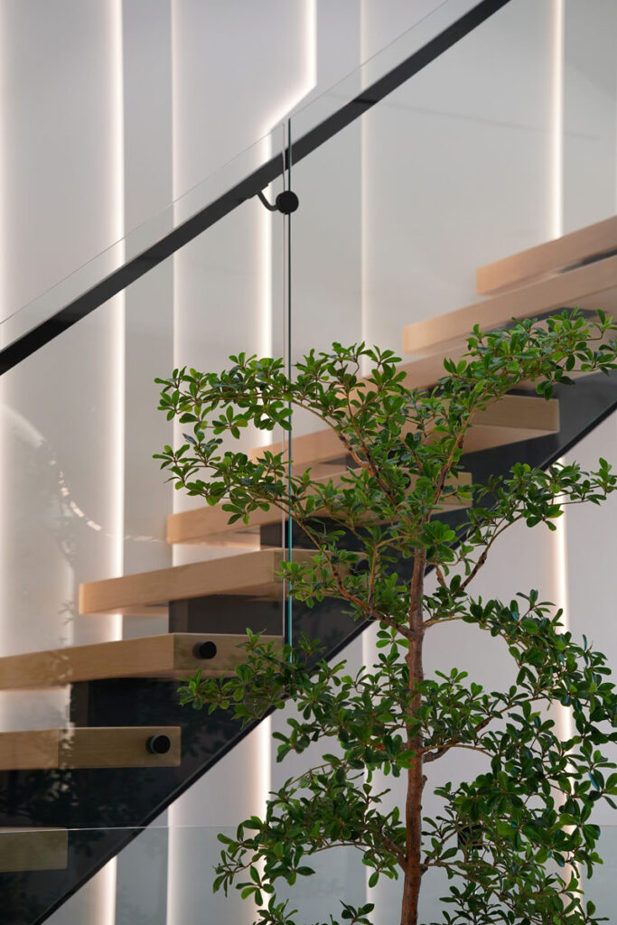 Modern floating staircase Toronto with wood treads, black steel stringer, and integrated vertical LED wall lighting