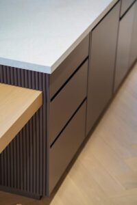 Modern custom cabinetry Toronto with wood drawers, fluted base, and stone countertop